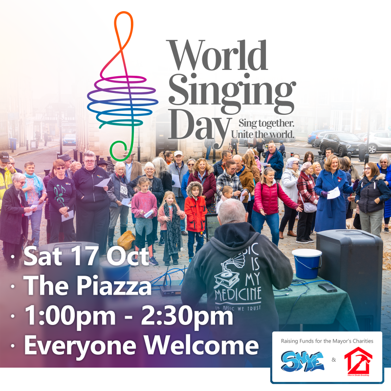 Photo of a crowd in Brackley singing together. World Sining Day logo at the top. White text reads 'Sat 17 Oct, The Piazza, 1:00pm - 2:30pm, Free Entry